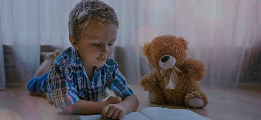 Teddy bear and child with book on floor