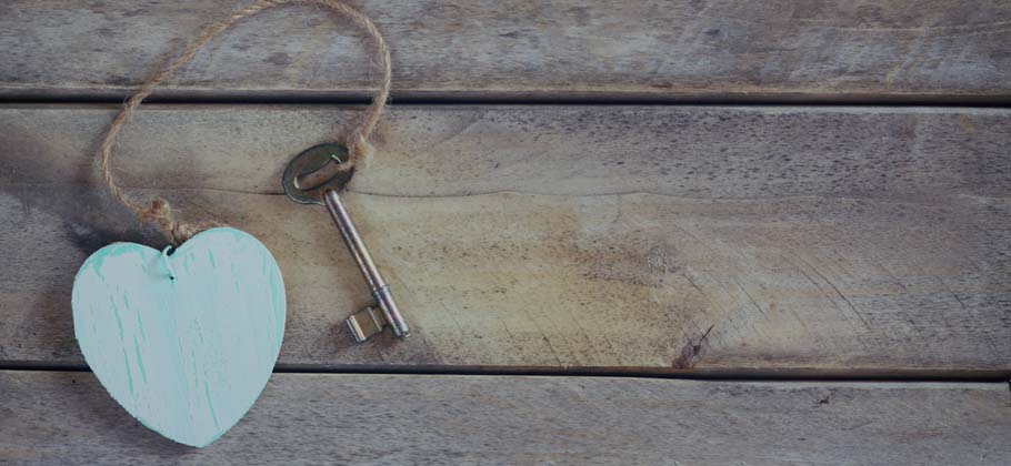 Vintage key with a wooden heart on wooden background
